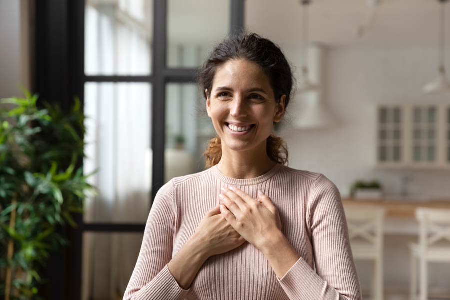 Photo of a smiling woman with her hands over her heart